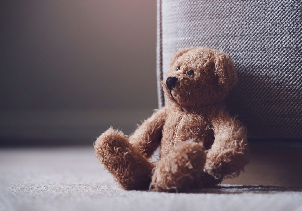 Teddy bear is laying down on carpet in retro filter, Lonely tedd